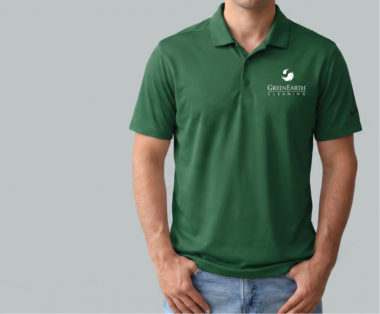 Person wearing a green polo shirt with a logo on a gray background